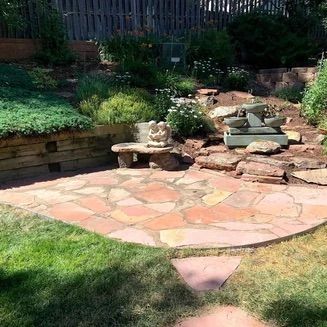 Stone patio with a tiered garden, a small water fountain, and a stone bench.
