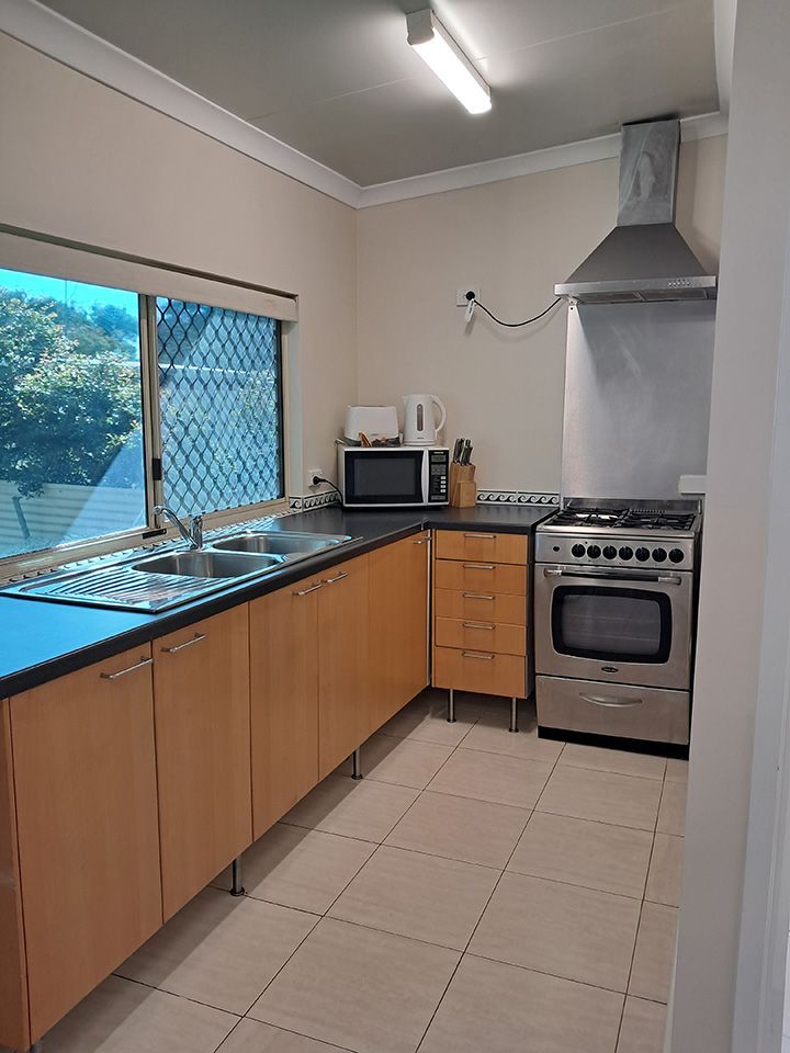 Small kitchen with wood cabinets, stainless stove, tiled floor, and a window over the sink.
