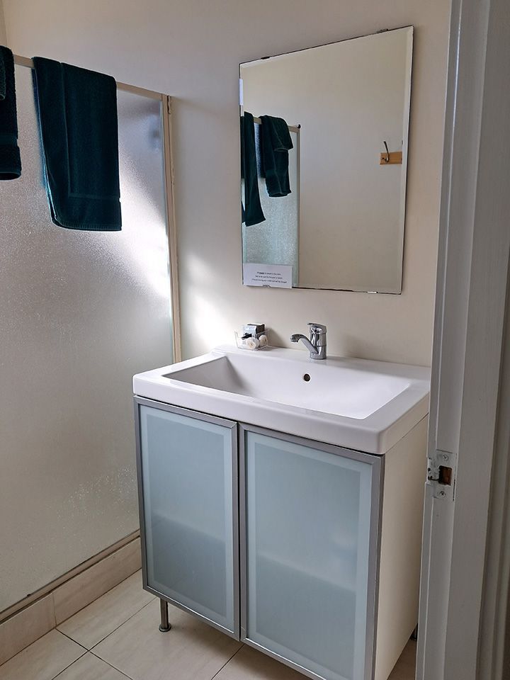 Bathroom sink vanity with mirror, pale blue frosted cabinet doors, and a dark towel hanging nearby