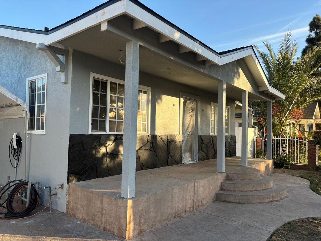 Front porch of a gray house with white columns, steps, and bicycles near the wall at sunset