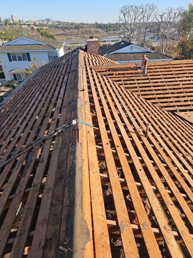 Damaged roof with missing tiles and exposed rafters on a house in a residential area