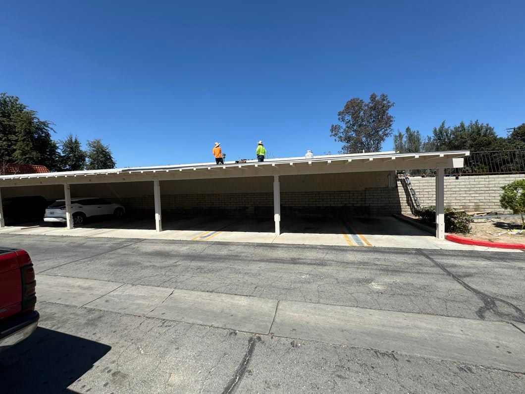 Covered parking lot with two workers on the roof under a clear blue sky