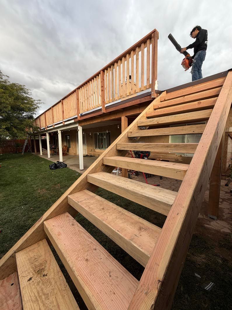 Outdoor wooden stairs beside a raised deck, with a person standing at the top holding a camera.