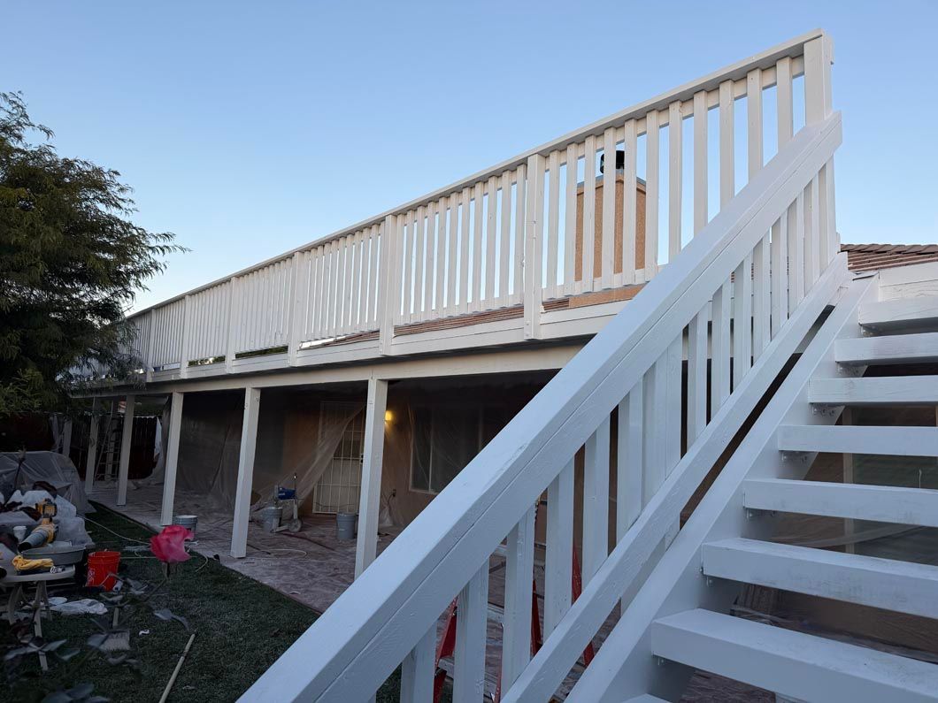 White-railed outdoor staircase leading to an elevated deck beside a house