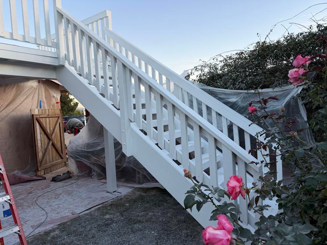 White outdoor staircase with railings beside a garden and flowers