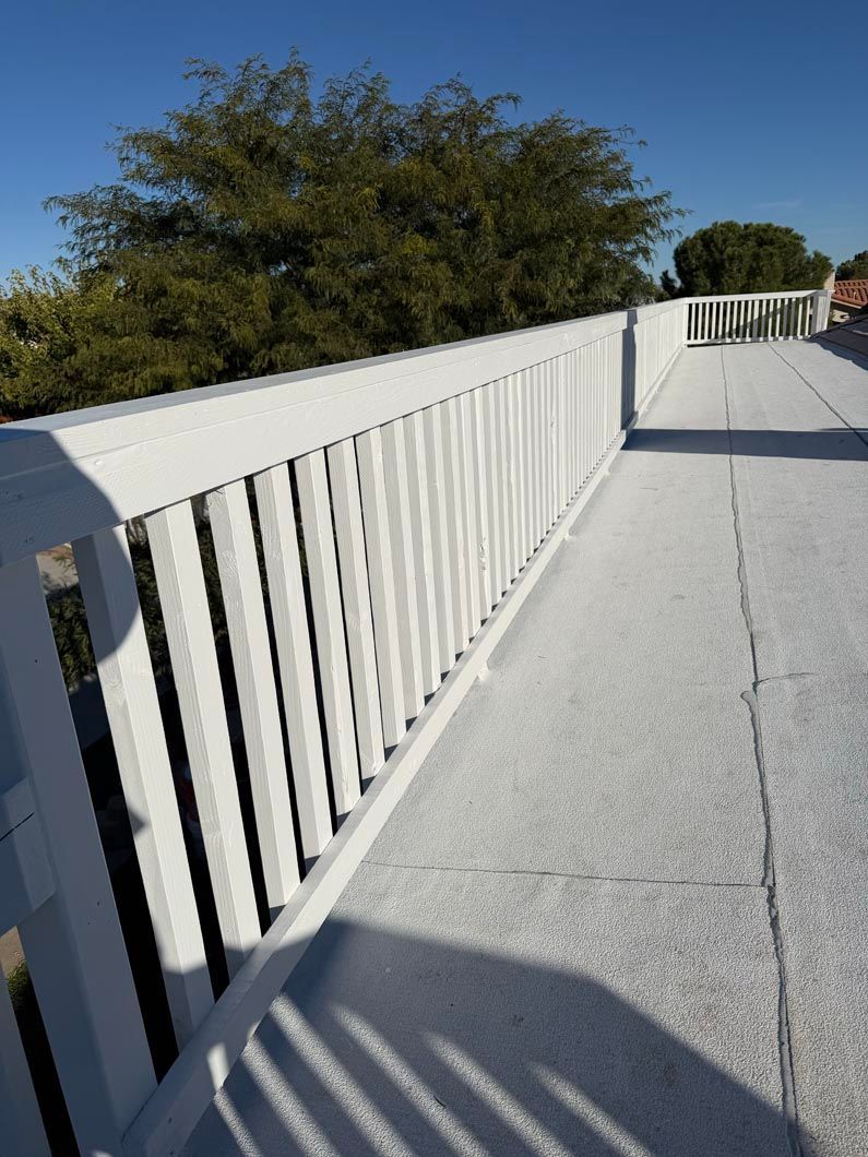 White railing along a sunlit ramp with trees in the background