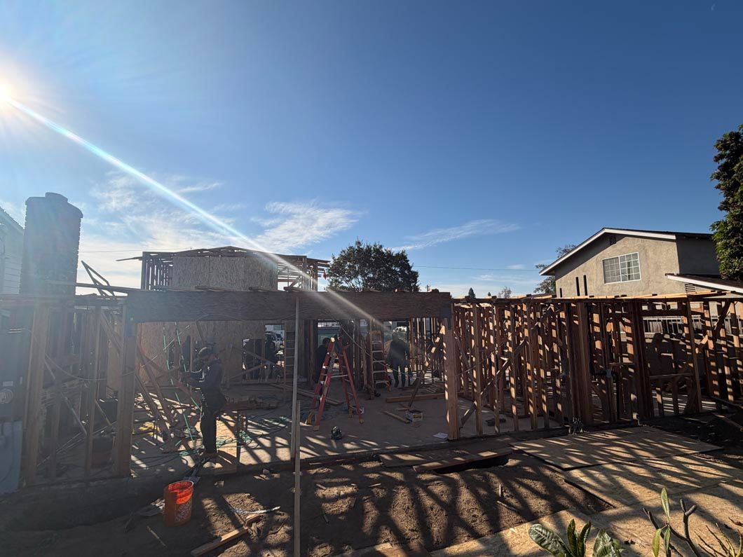 Backyard construction site with wooden framing, bright sun, and clear blue sky