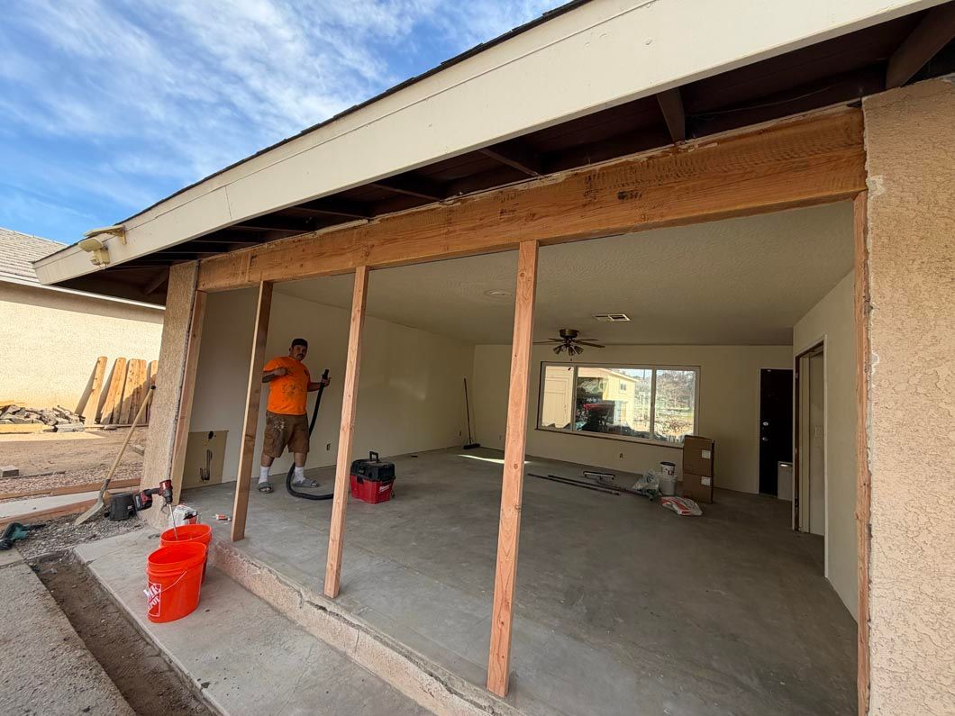 Partially demolished storefront with exposed wooden studs and a worker in an orange shirt inside