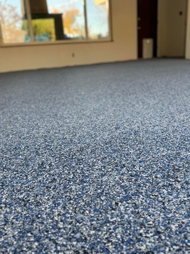 Low-angle view of blue-speckled carpet in an empty room with windows and a doorway in the background