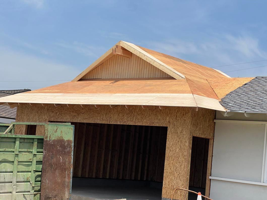 Partially constructed house with a corrugated metal roof under a blue sky