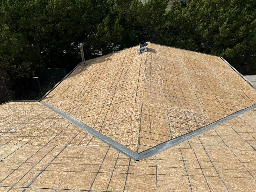 Wood shingle roof with a central ridge, bordered by trees in the background.