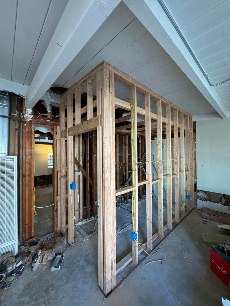 Partially framed interior wall under construction in a room with exposed studs and drywall