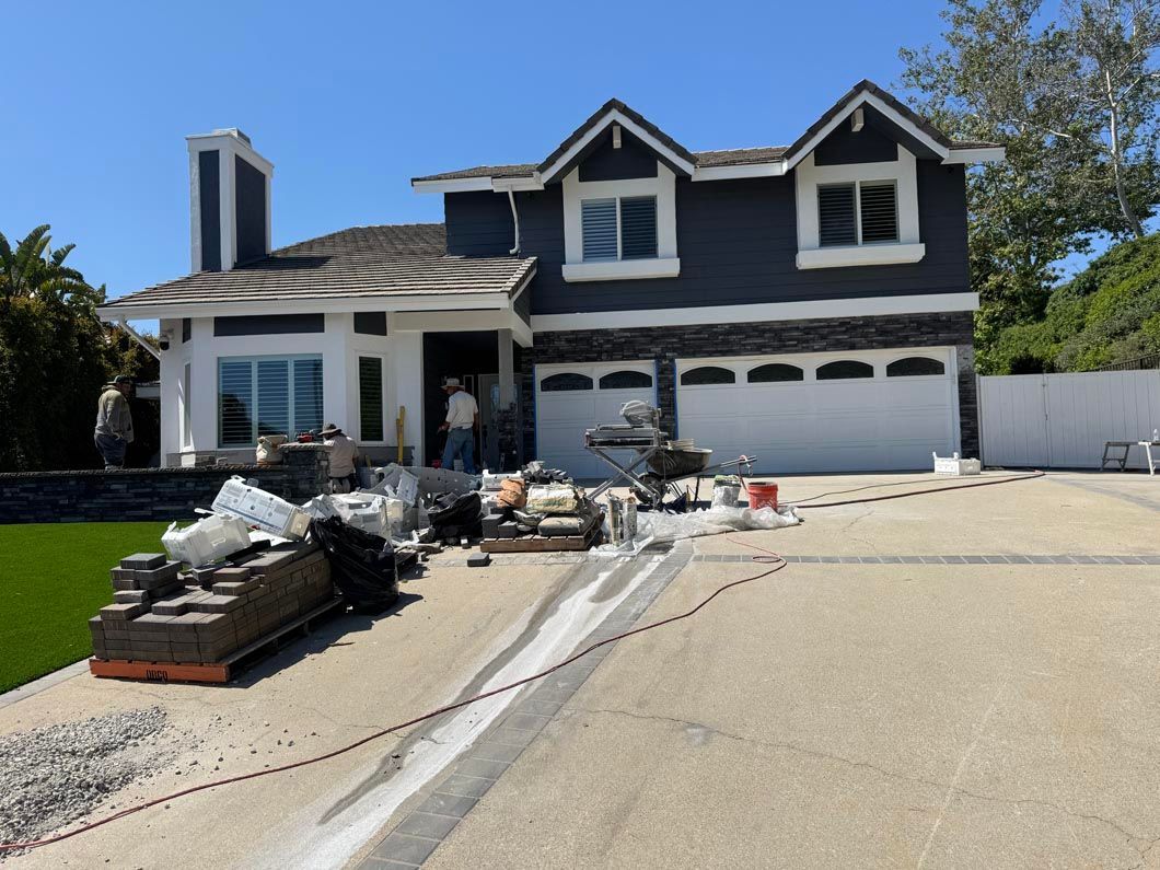 Two-story house with construction debris and materials scattered across the driveway and front yard