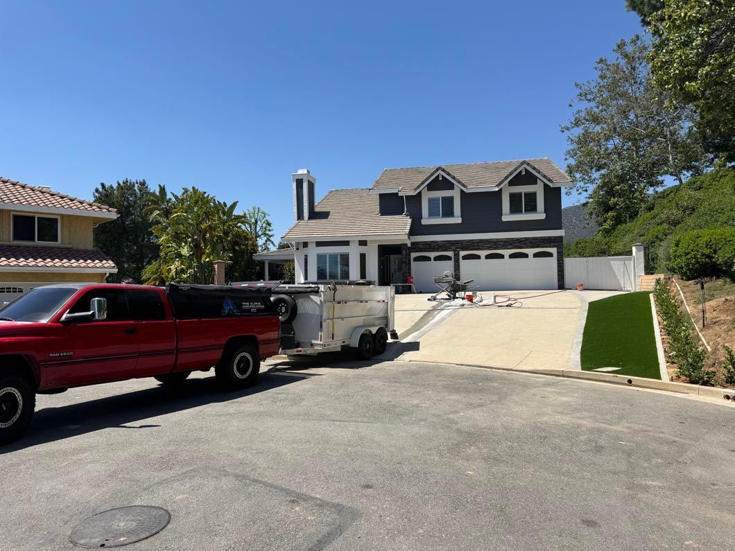 Suburban house with two garages, parked red truck and trailer, on a sunny day