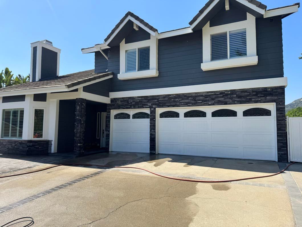 Suburban two-story blue house with white trim and three-car garage in bright sunlight