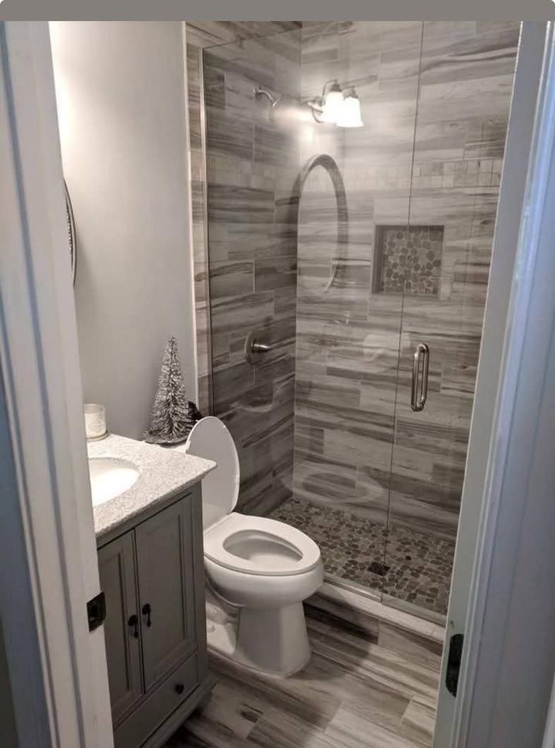 Small bathroom with vanity, toilet, and gray-tiled walk-in shower.