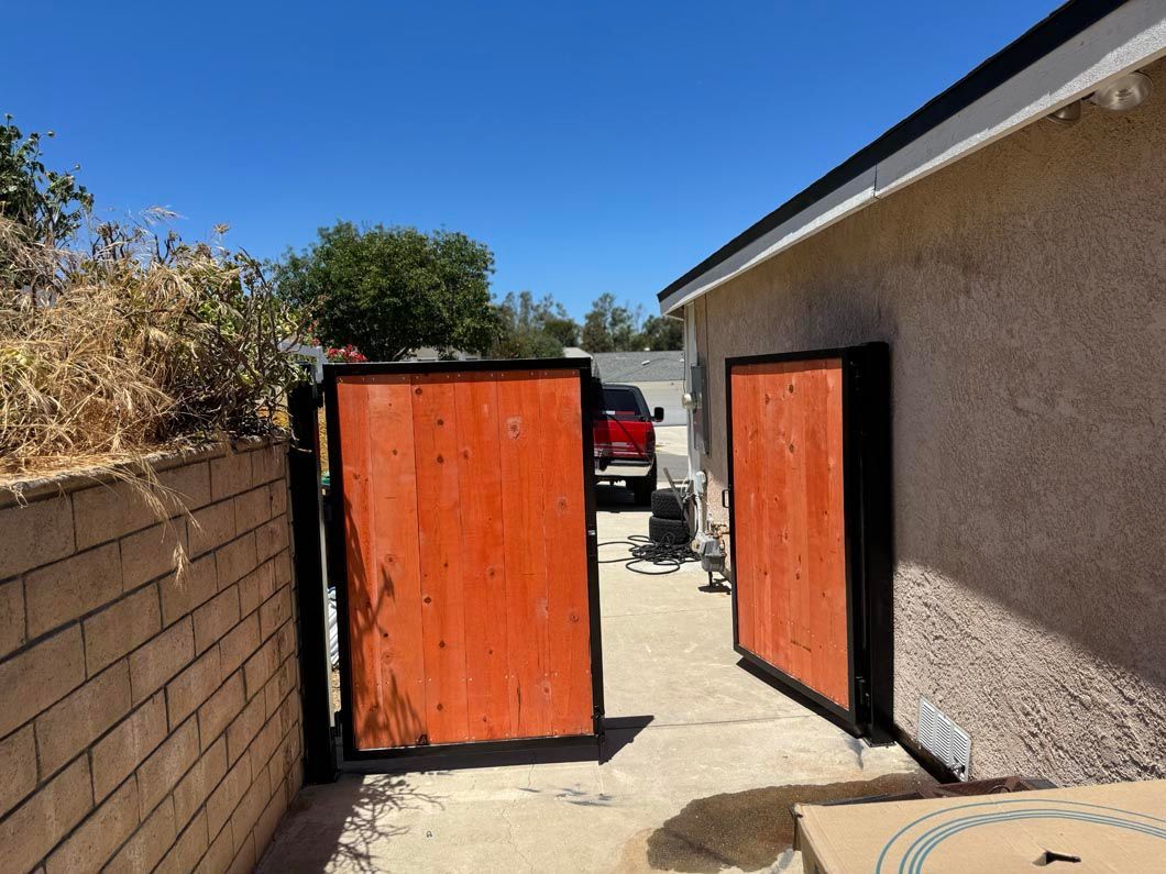 Orange garage doors in a narrow side yard beside a stucco house under a blue sky