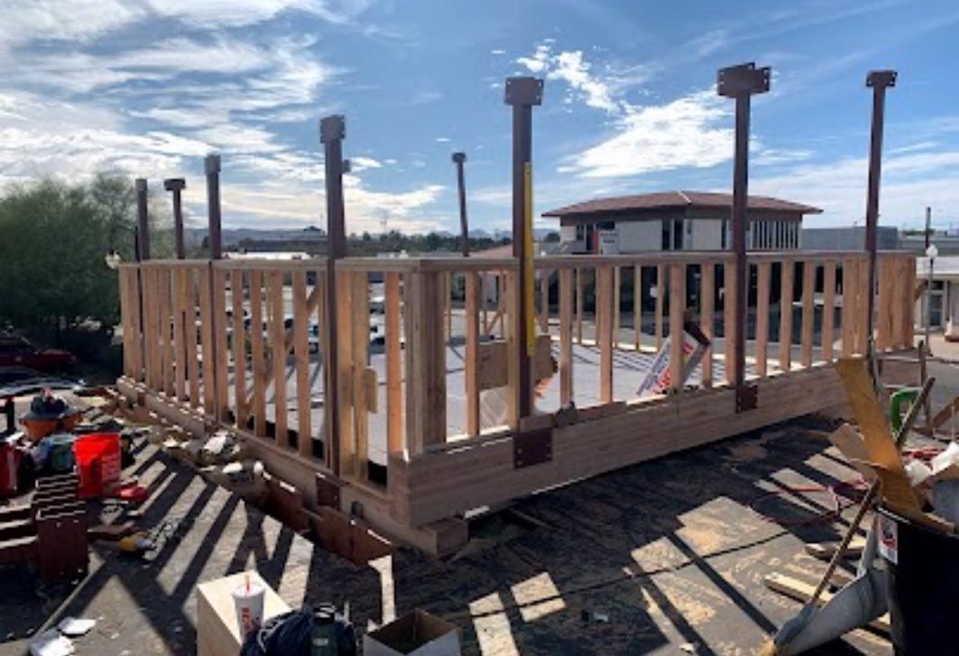 Partially built wooden deck frame with posts and railings on a rooftop under construction