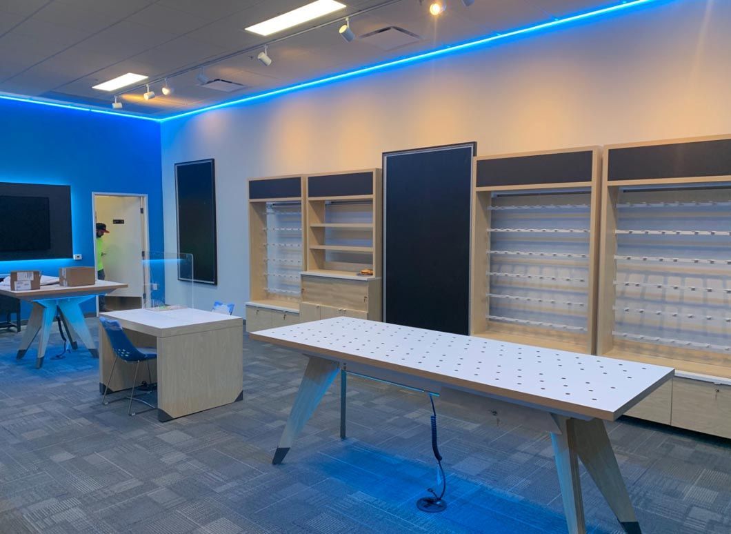 Empty modern room with blue LED ceiling lights, tables, and wall shelves