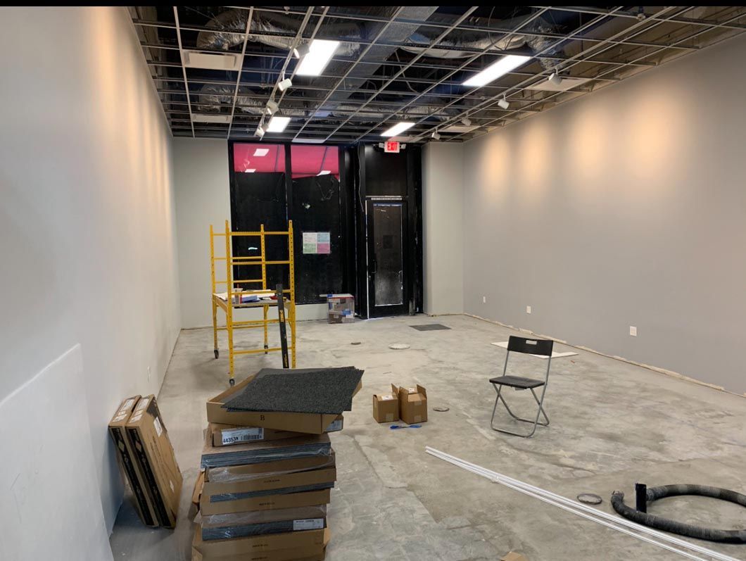 Empty hallway under renovation with ladders, construction materials, and exposed ceiling fixtures