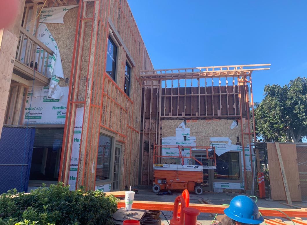 Construction site with brick building, scaffolding, and orange equipment under a clear blue sky