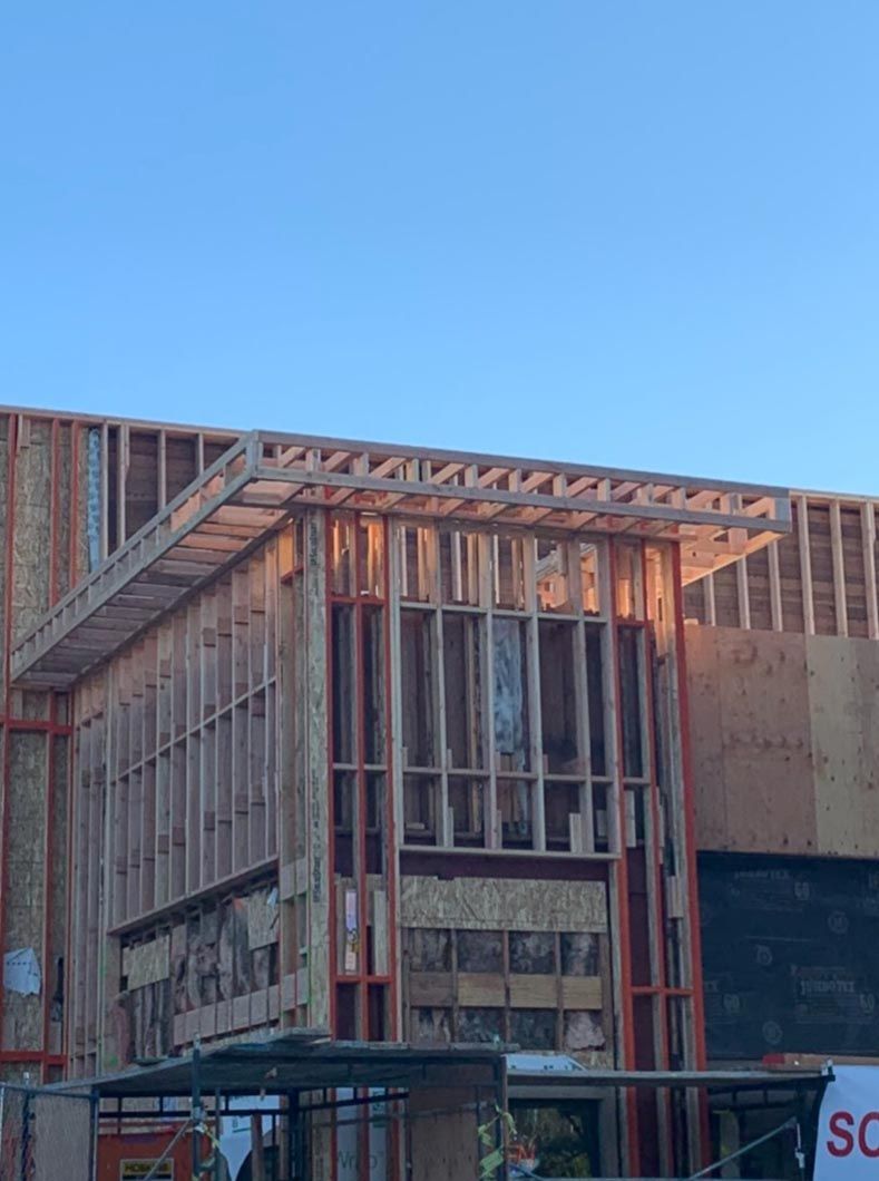 Partially framed wooden building under construction against a clear blue sky
