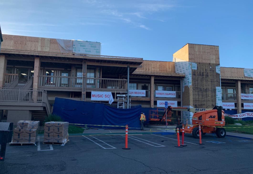 Construction site with workers, orange lift, and building facade under renovation