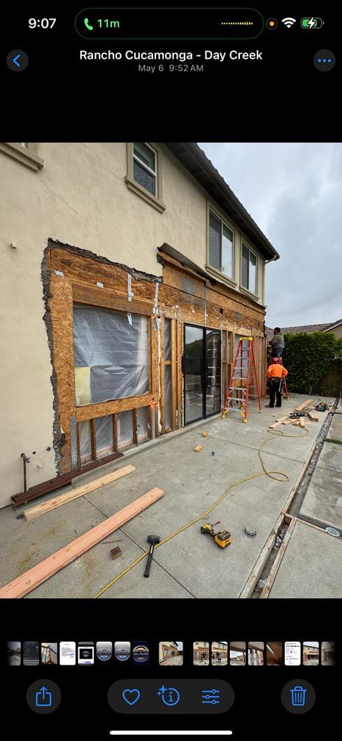 House exterior under renovation with exposed brick, new framing, and a worker near the front door.