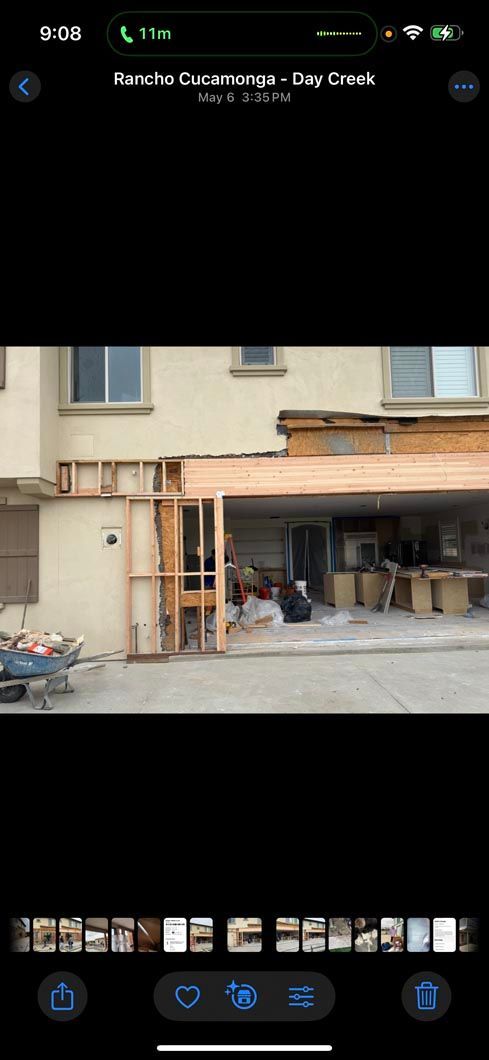 Phone gallery screen showing a blurry photo of a beige building exterior with a carport and parked items underneath