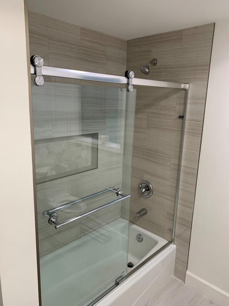 Glass shower enclosure with chrome bar and towel rail in a tiled bathroom