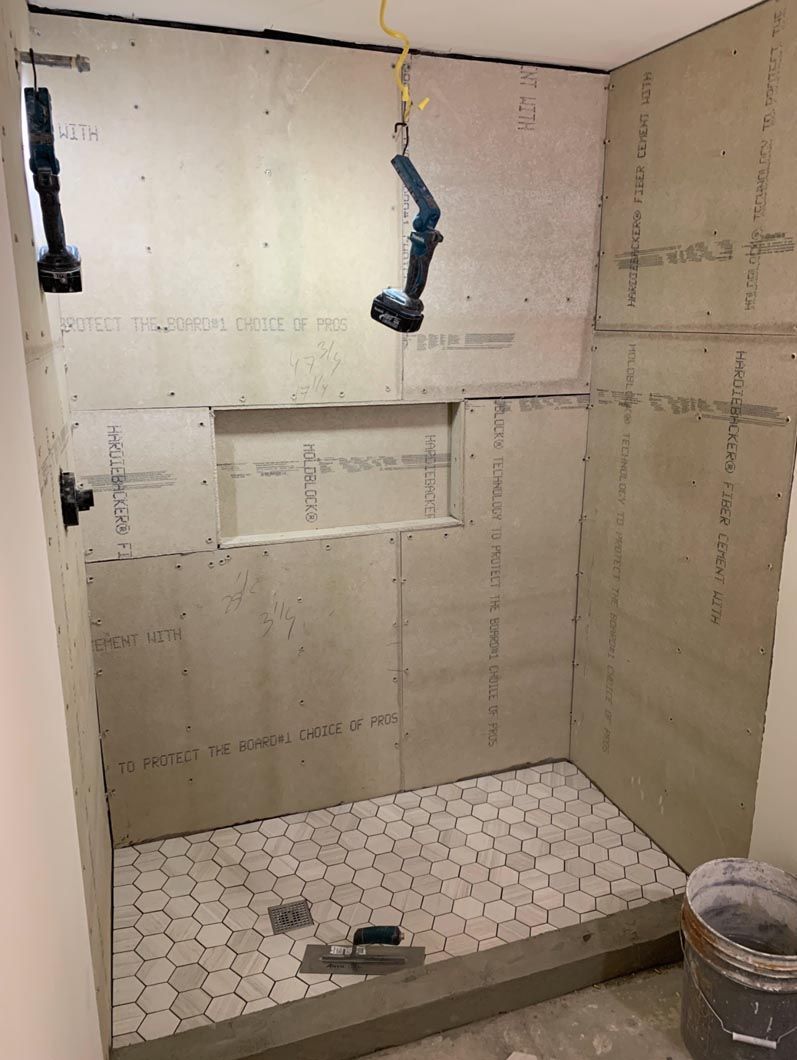 Partially tiled bathroom shower under renovation with exposed wall panels and hanging fixtures