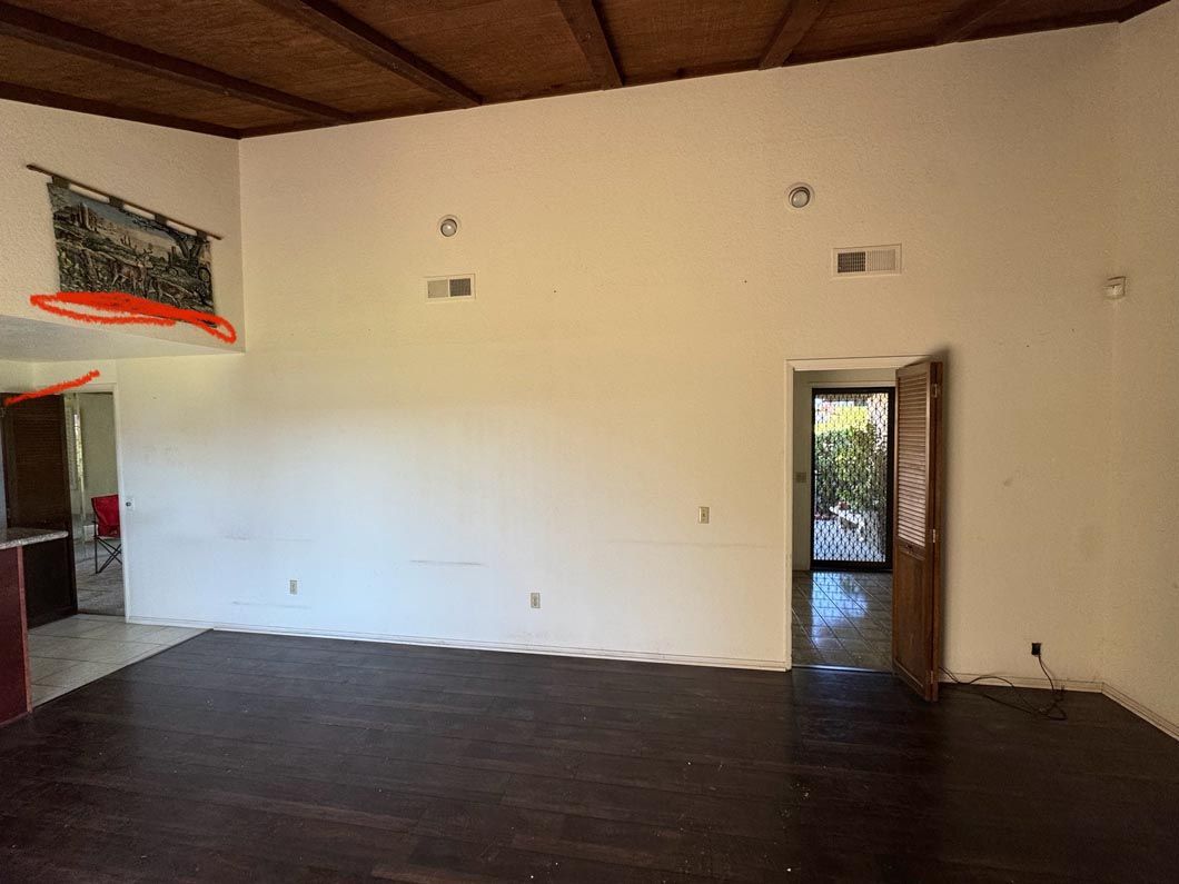 Empty room with dark wood floor, white walls, and open doorways to a brighter area