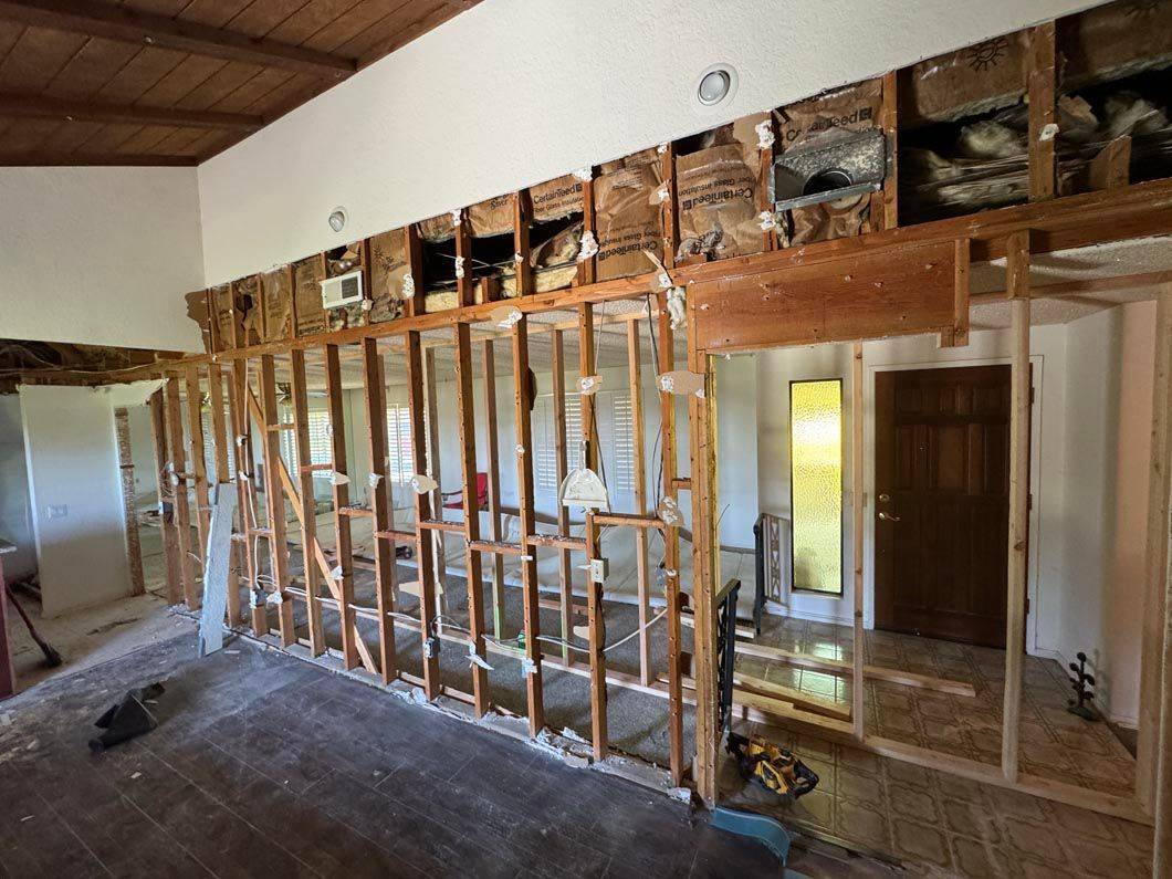 Interior room under renovation with exposed wooden wall studs and partially removed drywall.