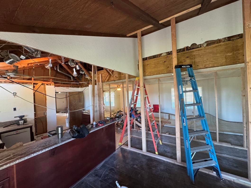 Partially renovated interior with exposed beams, ladders, and construction materials