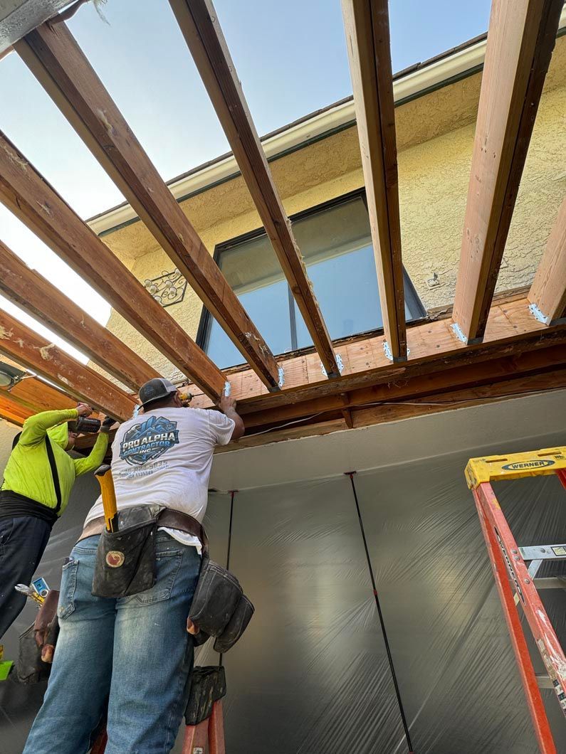 Two workers installing wooden ceiling beams at a construction site, viewed from below