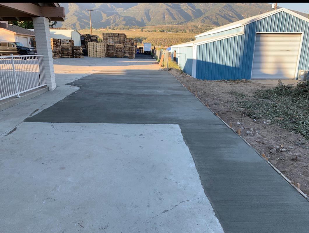 Concrete path beside blue-and-white buildings leading toward a mountain view