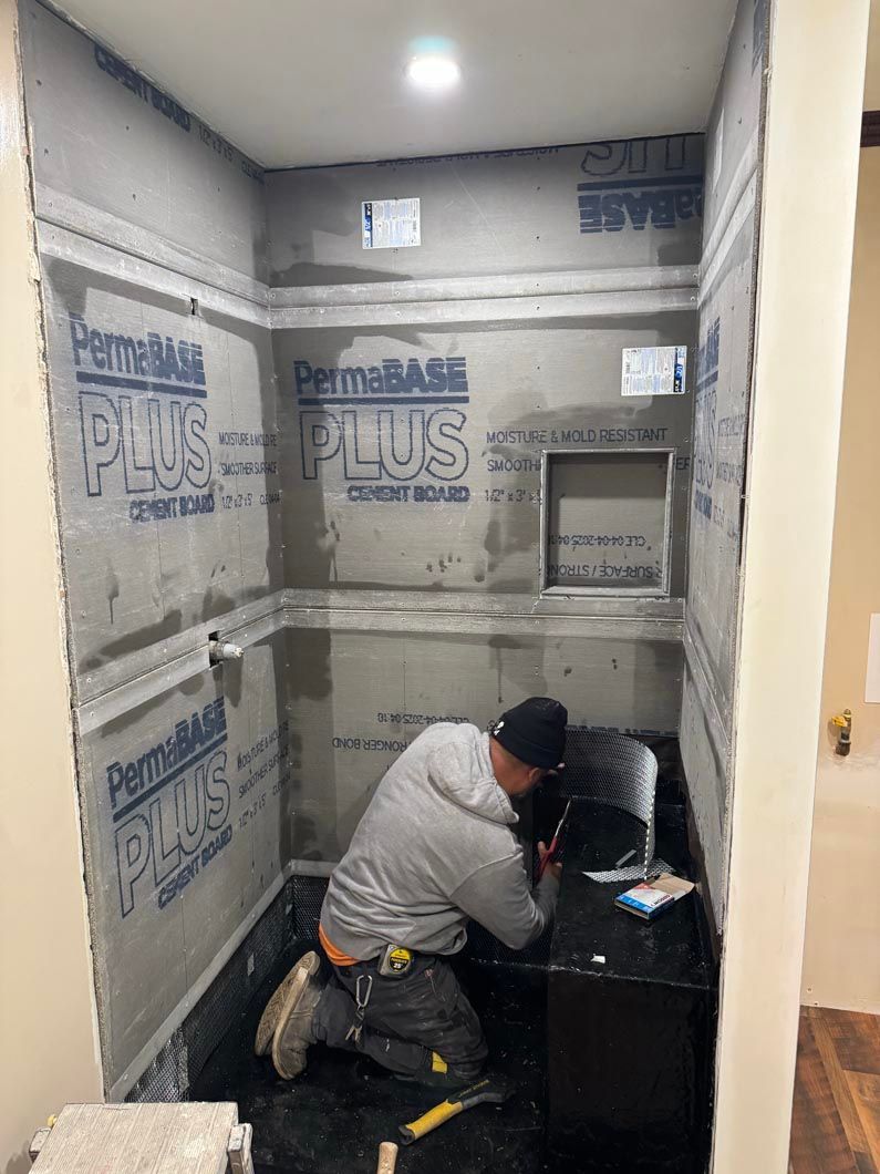 Worker installing insulation in a small room with exposed walls and a recessed wall opening.