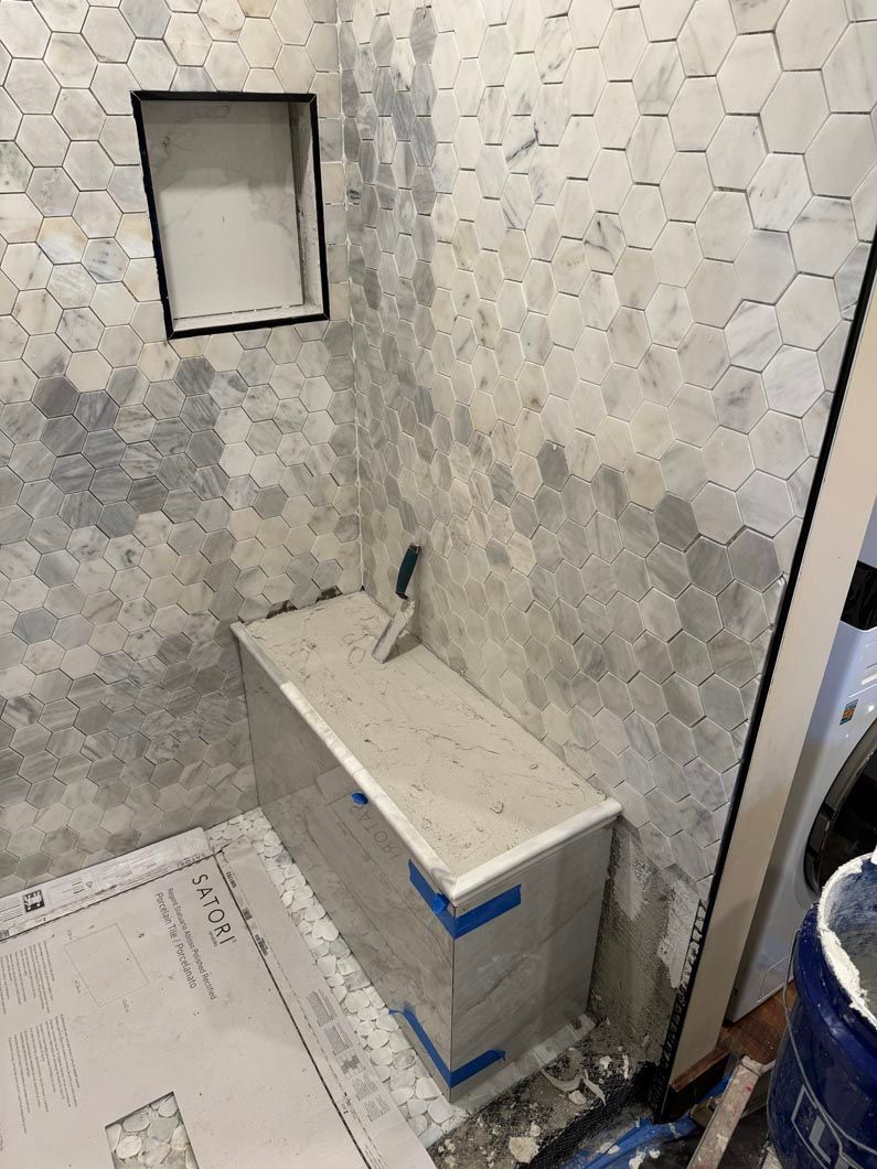 Small bathroom with a toilet, hexagon tile walls, and a wall mirror above the tank.