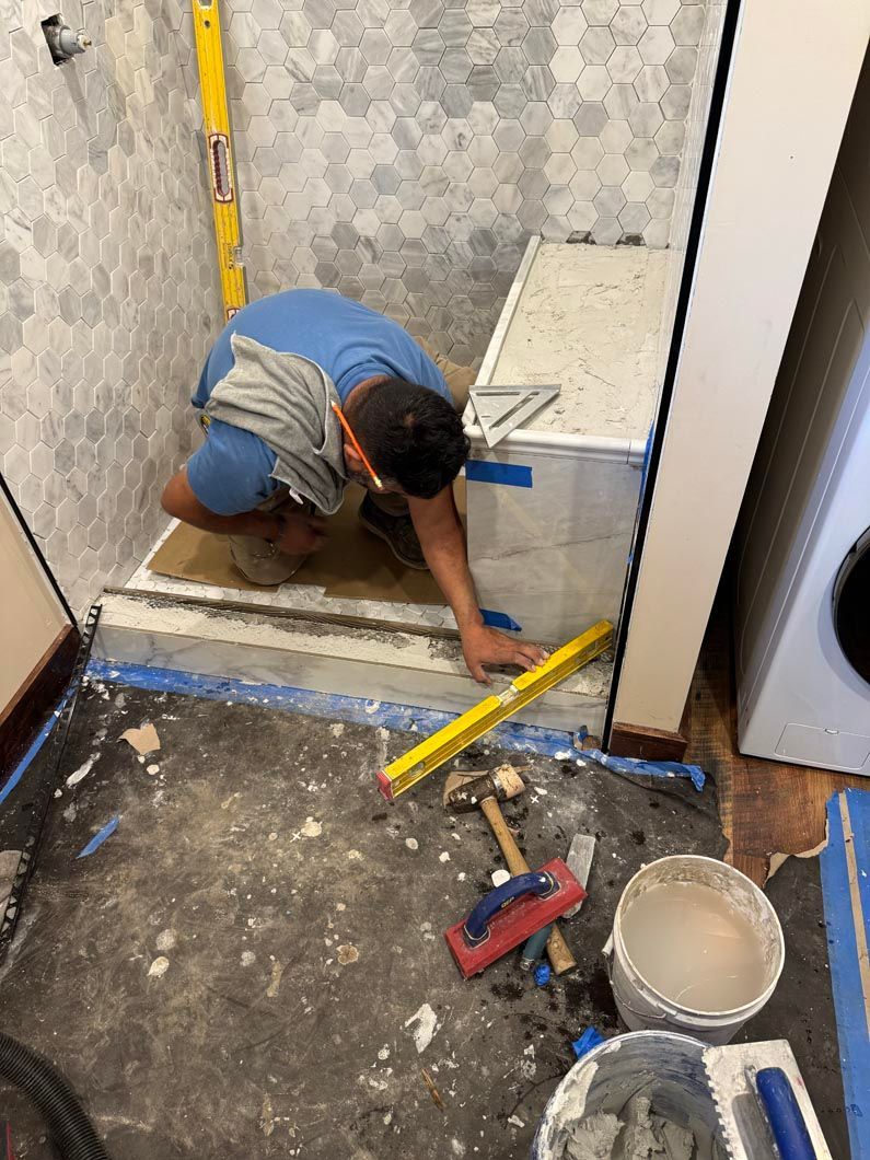 Worker measuring floor near a doorway with a tape measure during renovation.