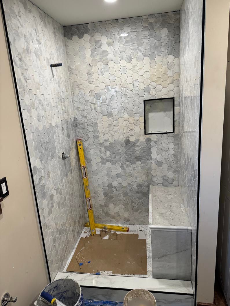 Small tiled shower stall under construction with a yellow level tool and unfinished floor.