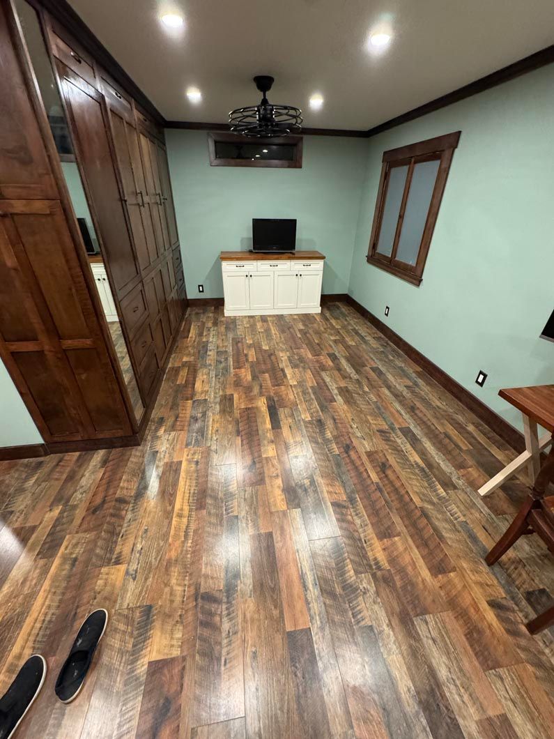 Empty living room with wood floors, mint walls, white cabinet, TV, and recessed ceiling lights