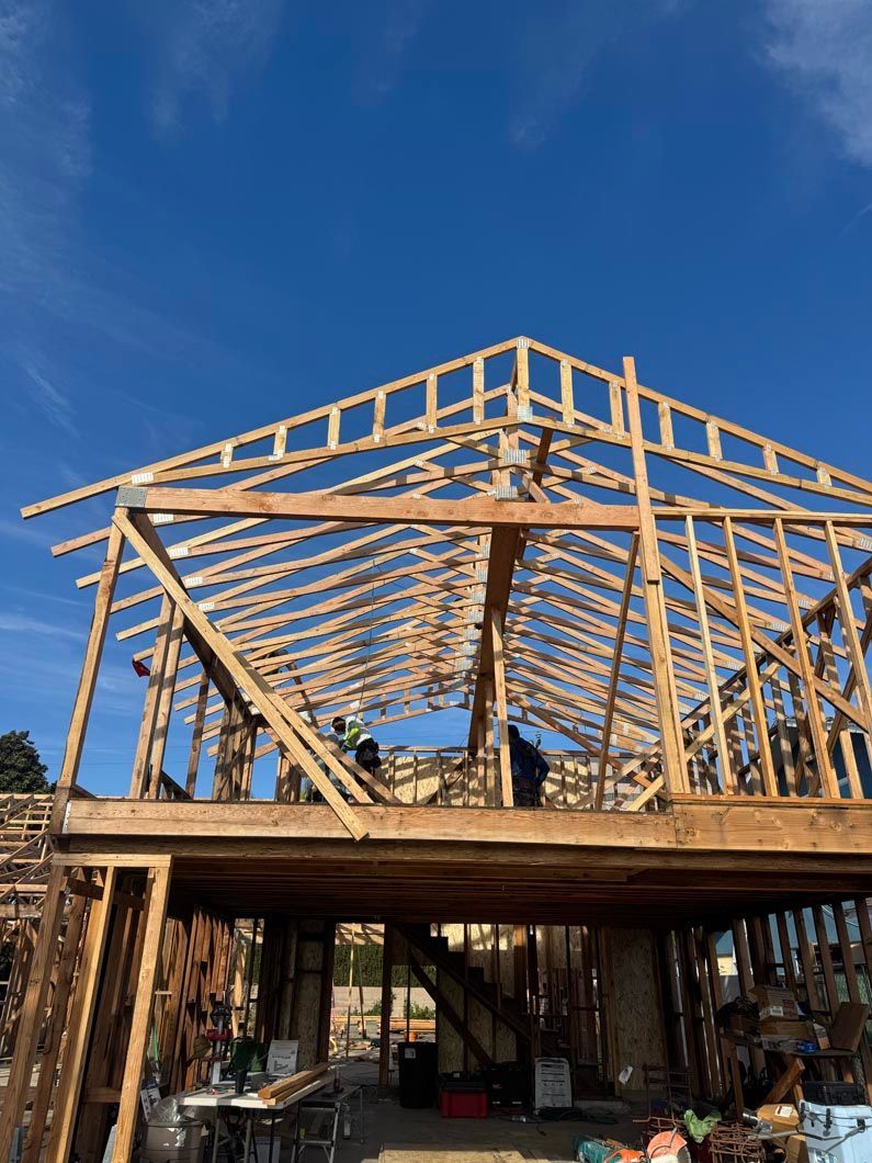 Partially built wooden house frame against a clear blue sky