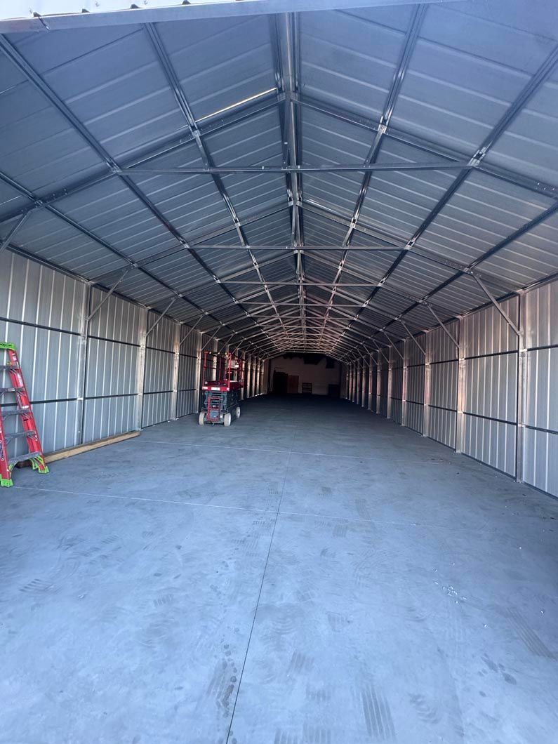 Empty corrugated-metal warehouse interior with high arched roof and concrete floor