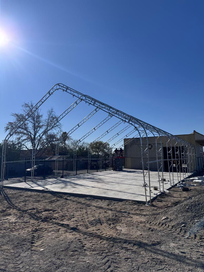 Partially built metal frame structure on a concrete slab under a bright blue sky