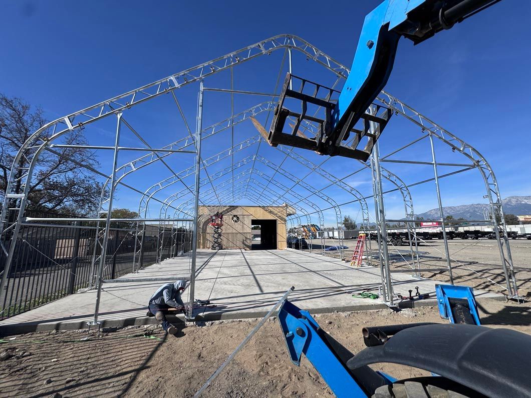 Construction site with a metal dome frame being assembled under a blue sky