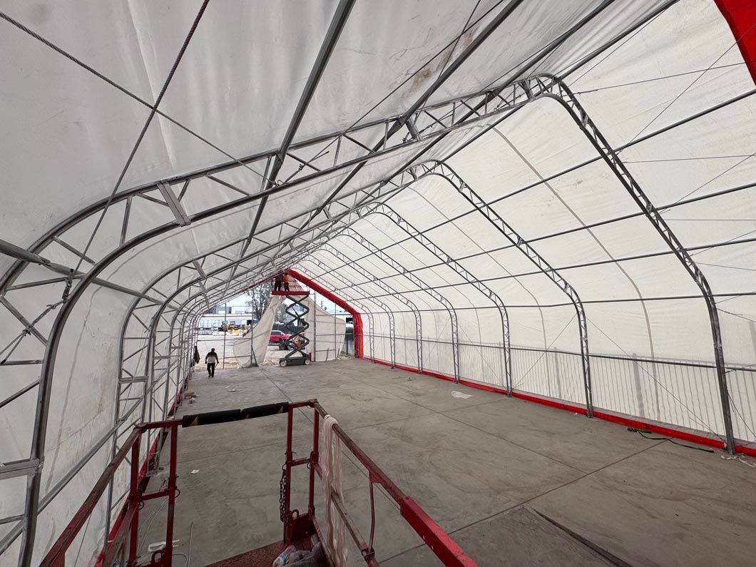 Covered tunnel-like walkway with white arched canopy and red metal frame