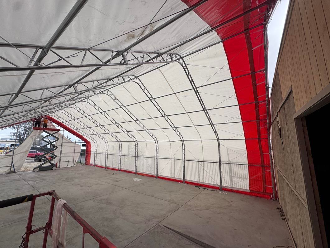 Empty covered walkway with white canopy, red side panels, and metal framework on a concrete floor