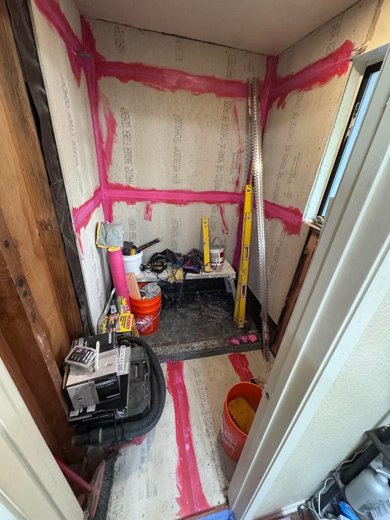 Small unfinished bathroom with pink waterproofing, exposed walls, and a toilet installation in progress