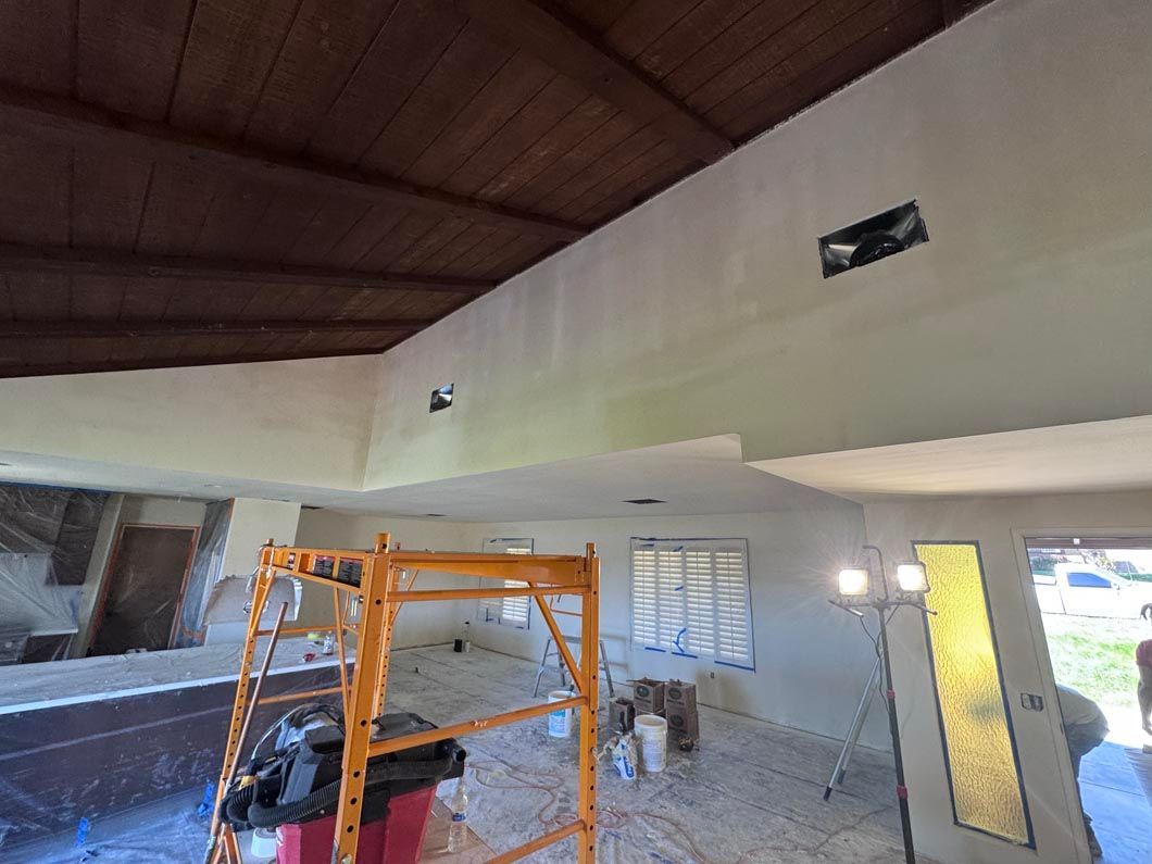 Interior under renovation with orange scaffolding, white walls, and a dark wood ceiling