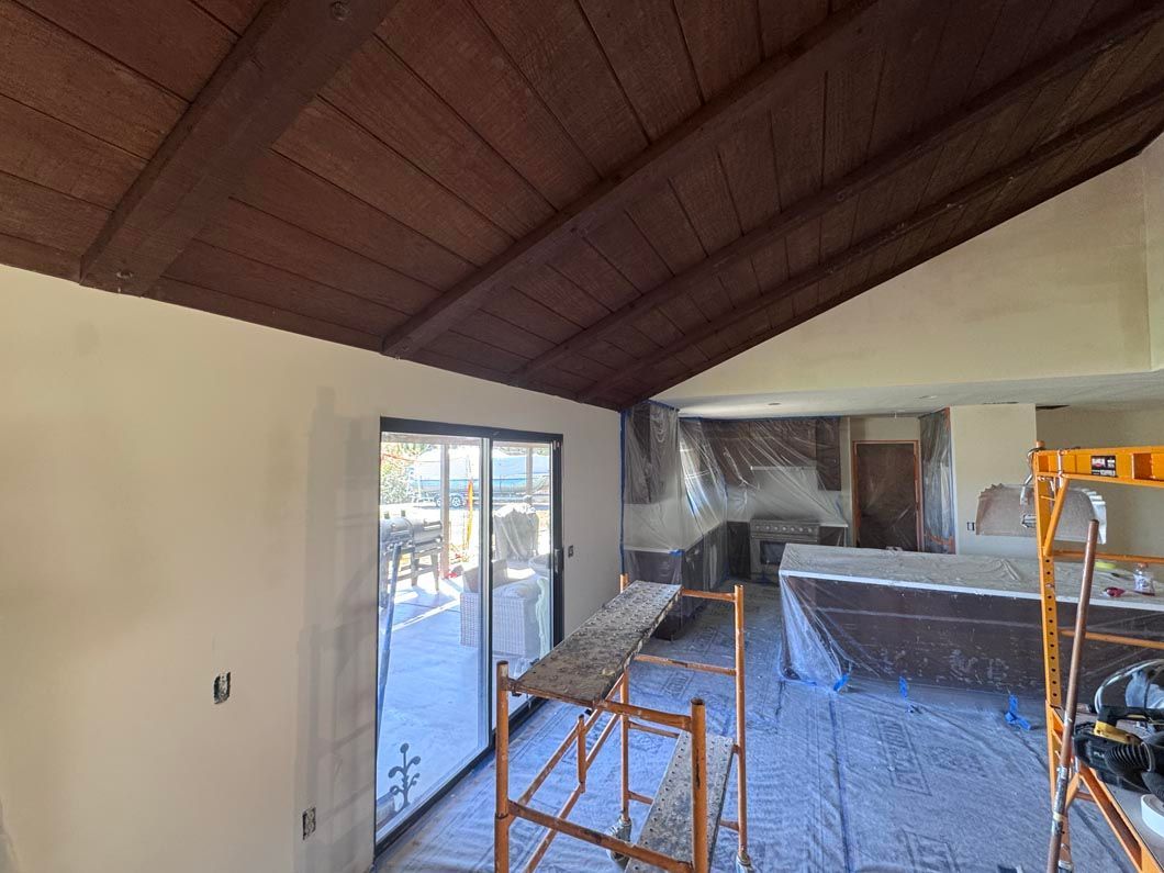 Empty room with vaulted wood ceiling, white walls, and construction materials inside.